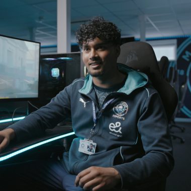 Male Esports learner sat in a chair next to a computer screen