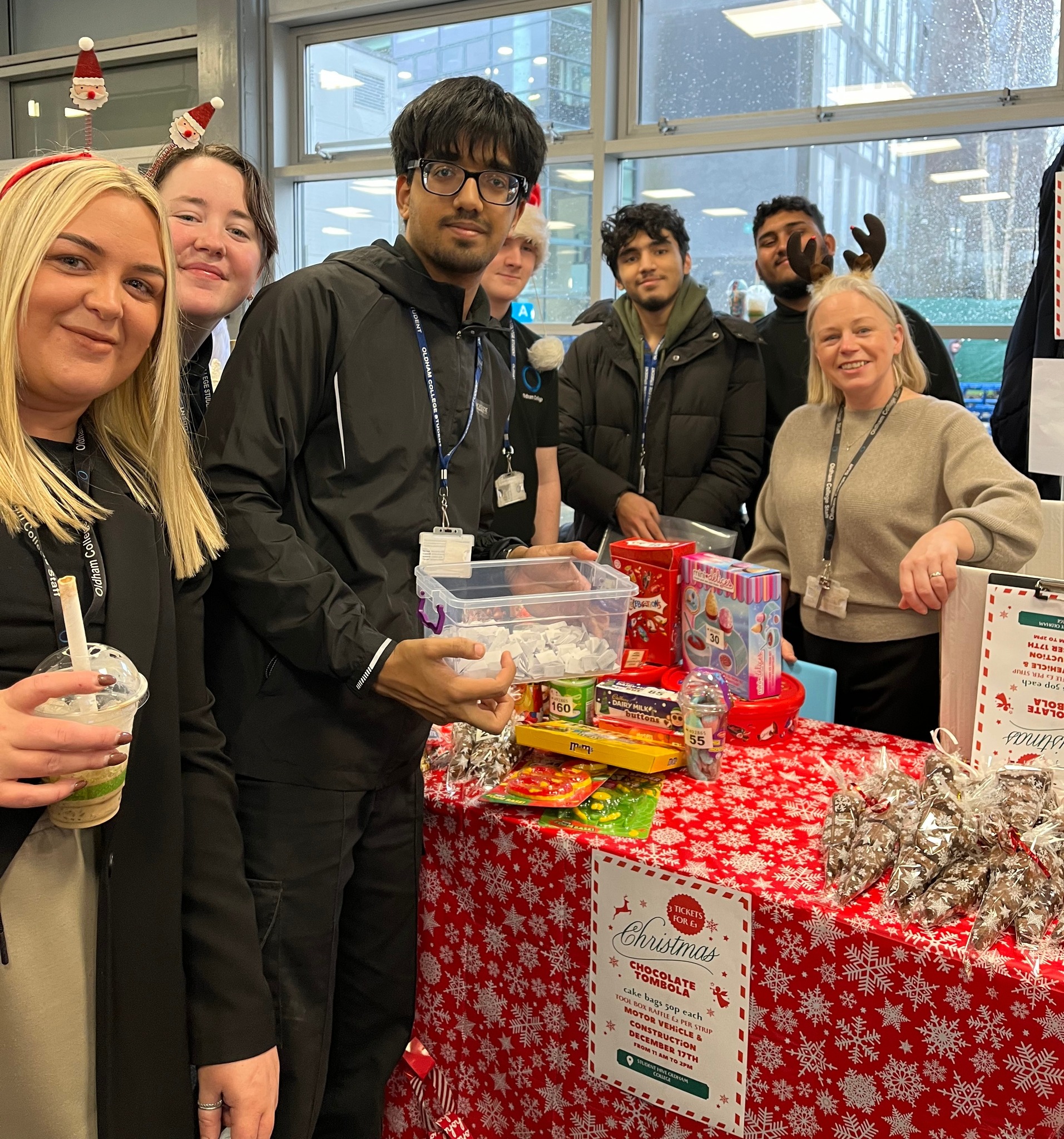 A group of staff and students stand around a table laid with a Christmas tablecloth and gifts.