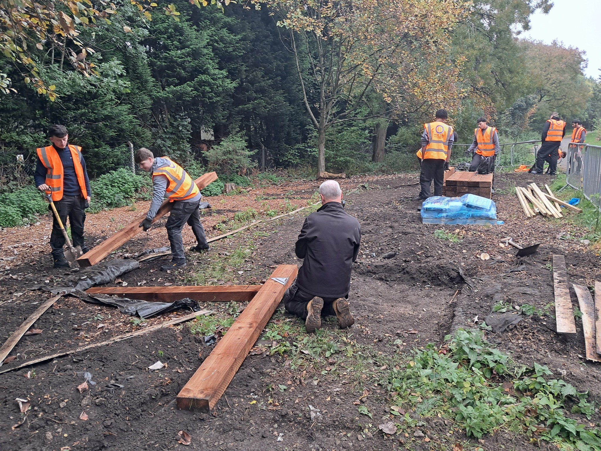 People in orange hi-vis jackets working outdoors.