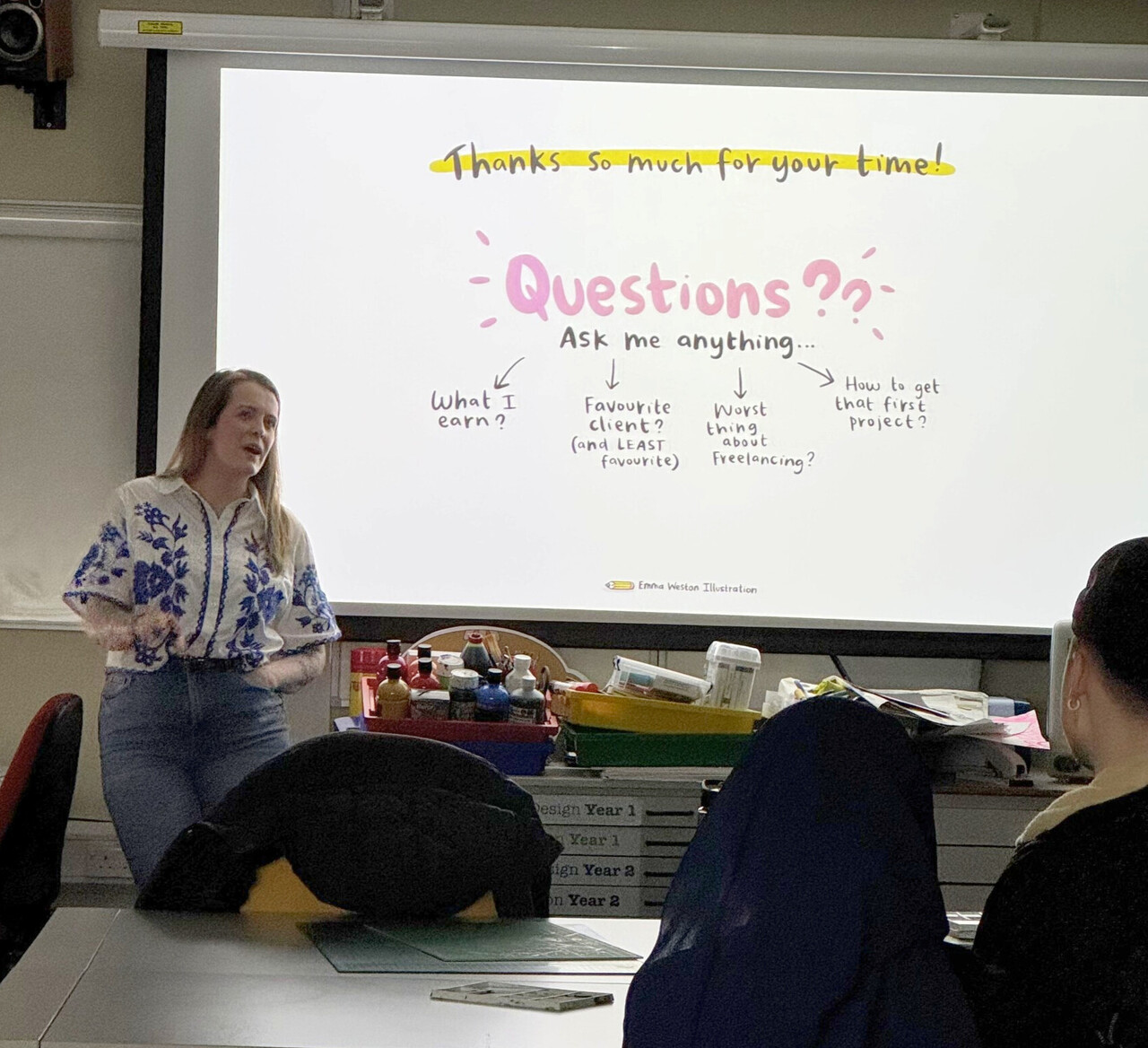 A person stands at the front of a classroom delivering a presentation