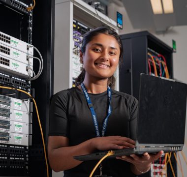 A female IT and networking student in a server room