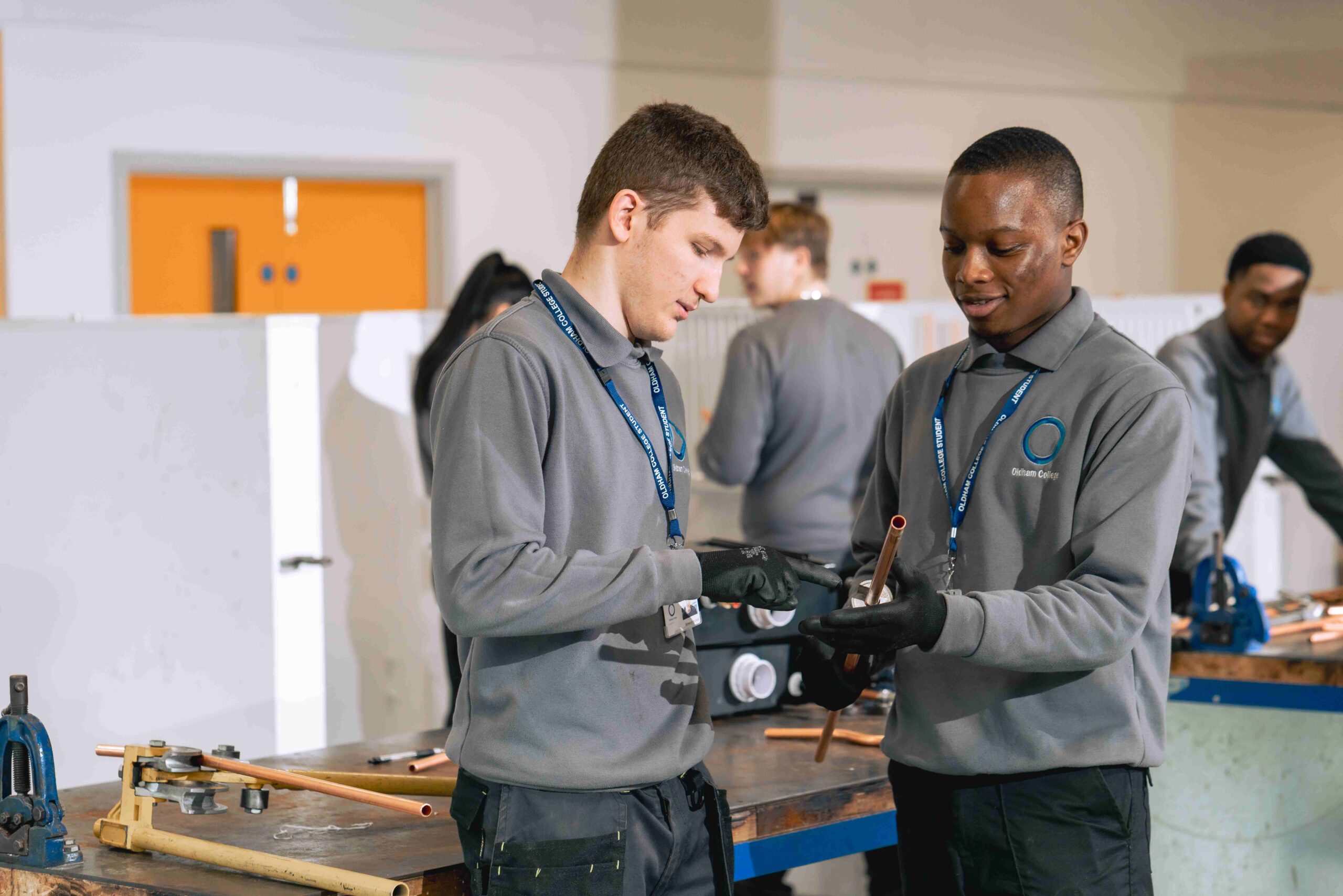 Two male plumbing apprenticeship students holding a pipe