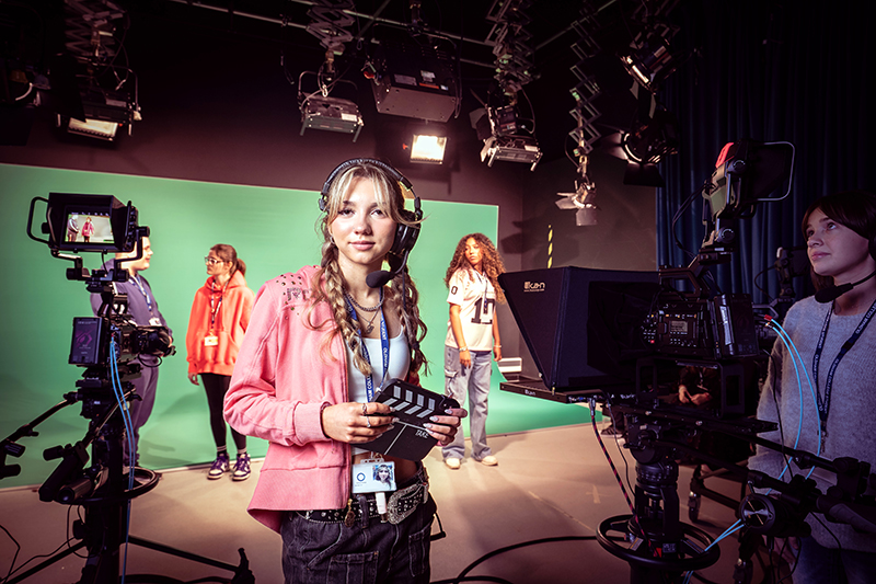 Female creative student stood in a tv studio wearing a head set