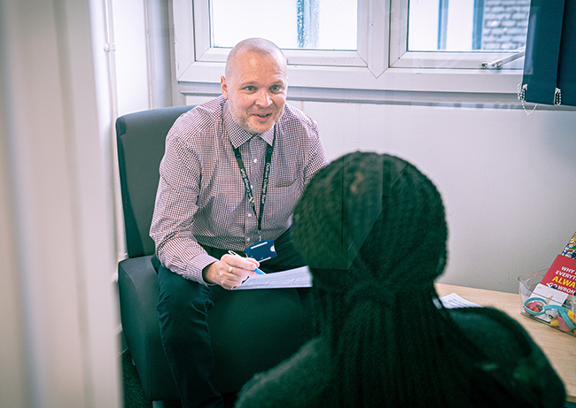 Male support staff member talking to college student