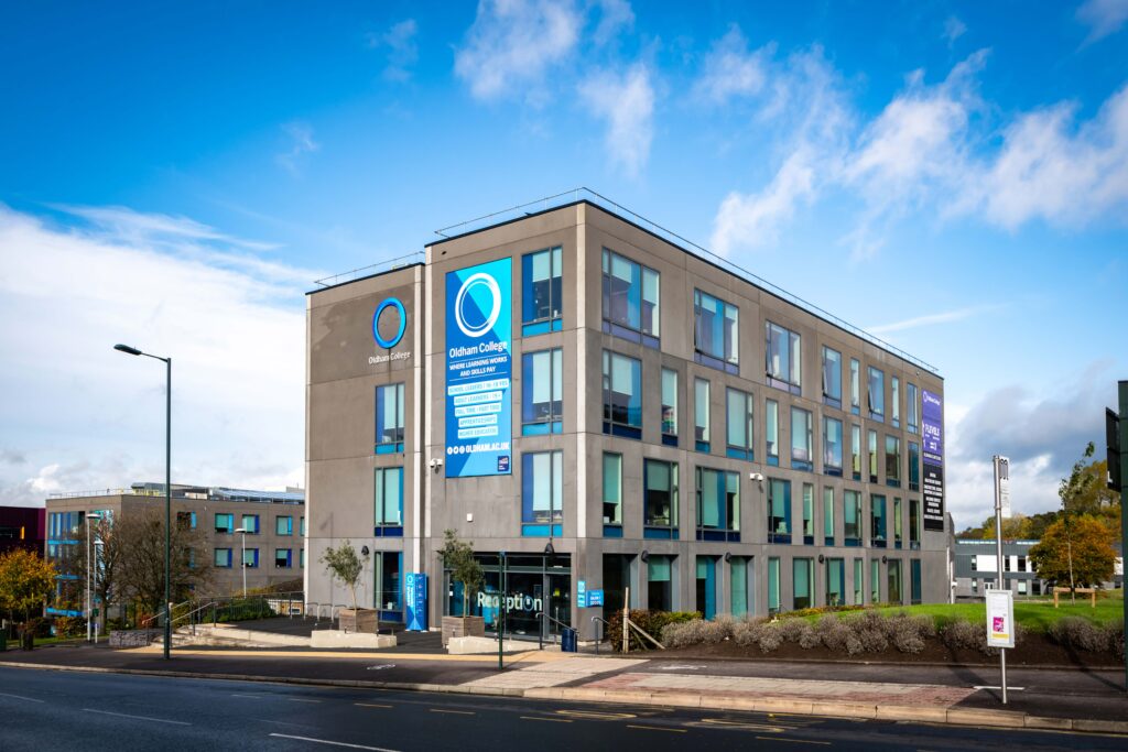 Oldham College's Campus Central, a large grey building, photographed on a sunny day.