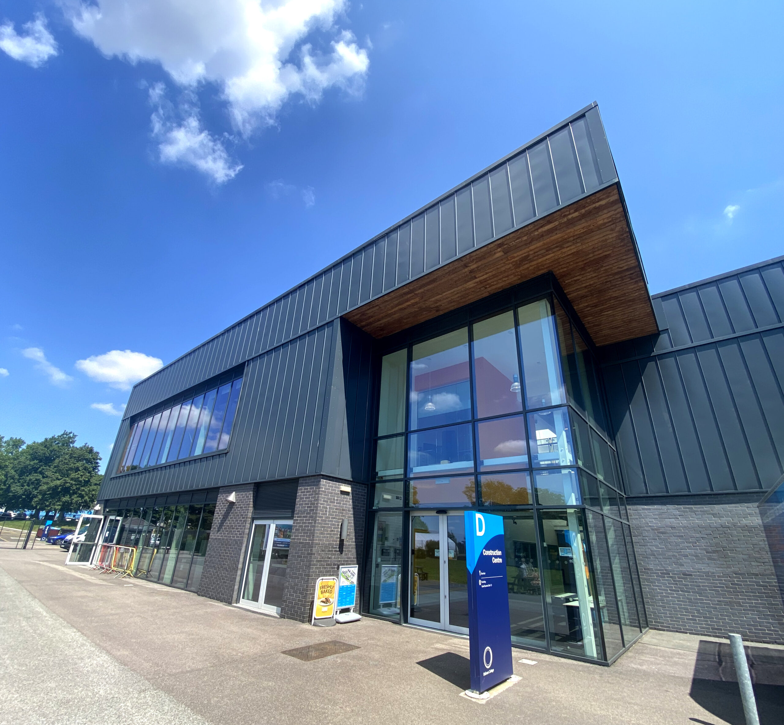 Oldham College Construction Centre, a large grey building, photographed on a sunny day.