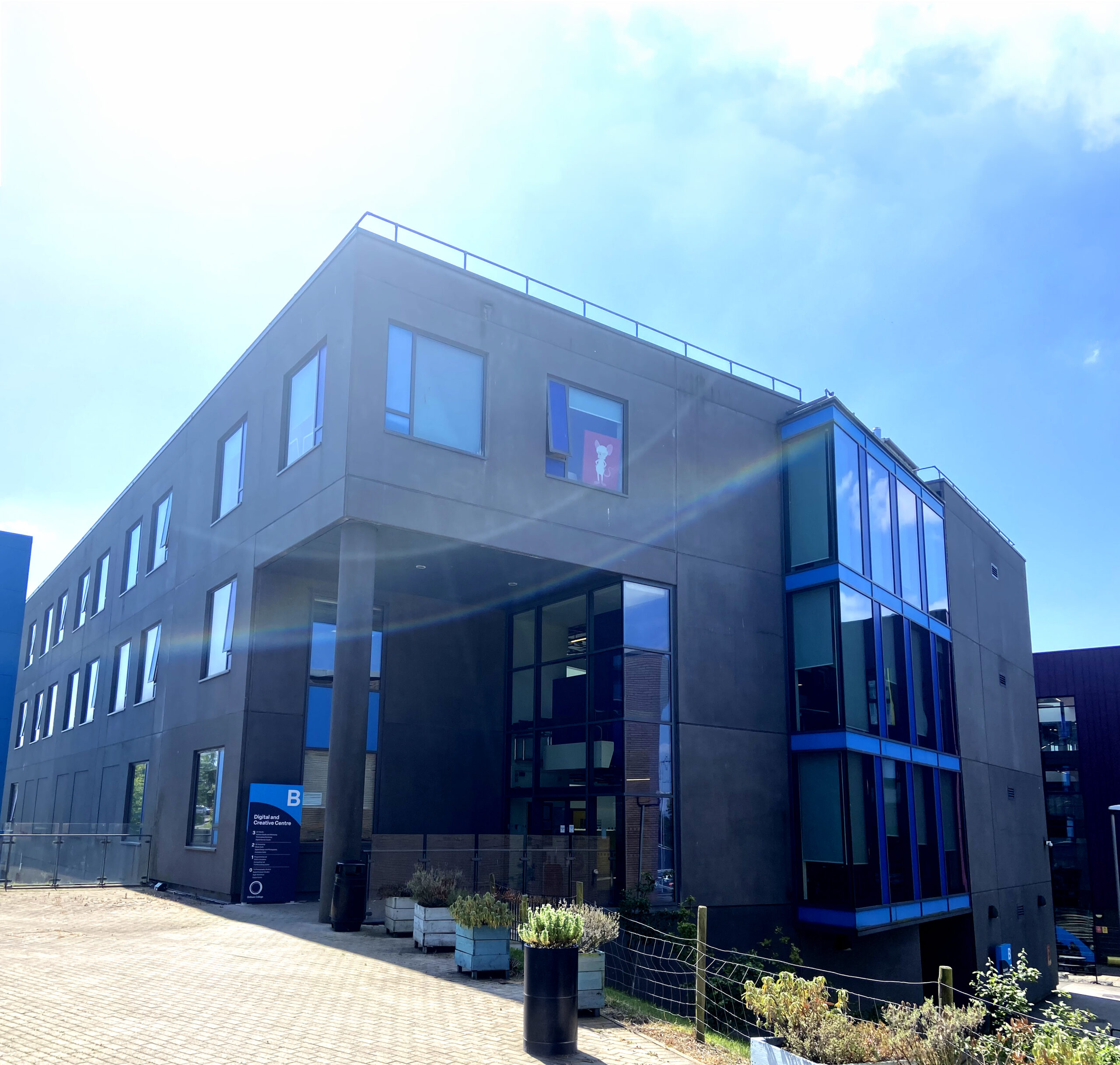 Oldham College's Digital and Creative Centre, a large grey building, photographed on a bright day.