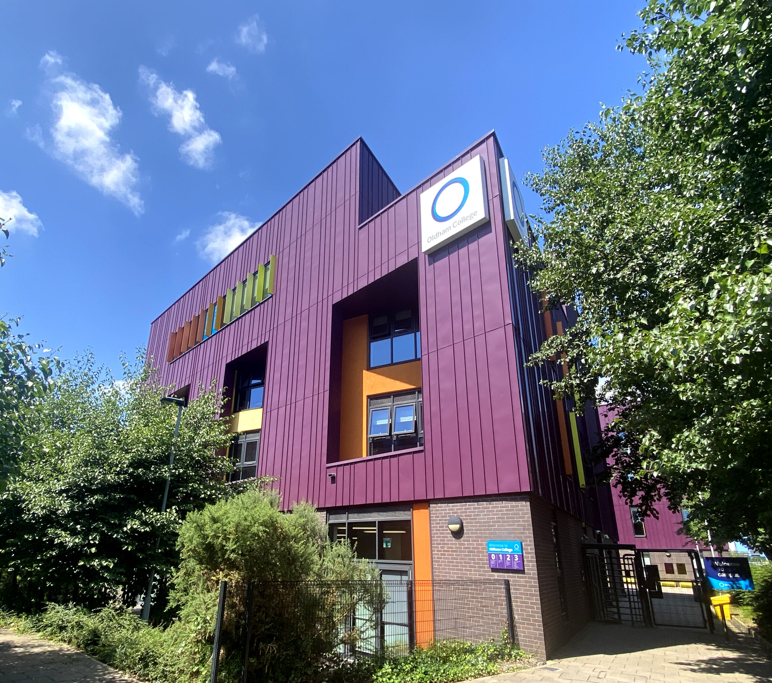 A photo of a purple building with Oldham College logo attached near its roof.