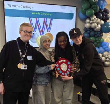 Four learners holding a shield and standing in front of a screen which reads 'FE Maths Challenge awards ceremony'