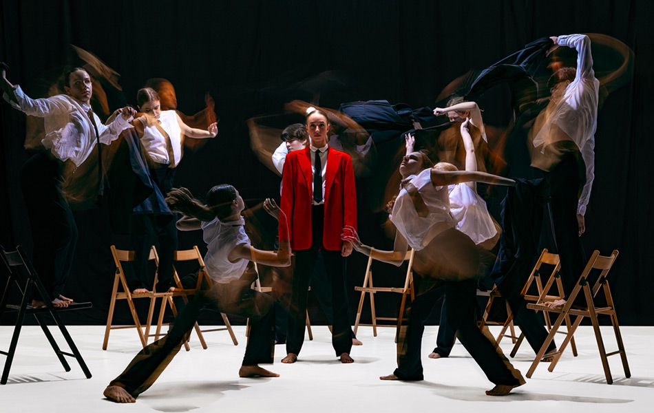 Students doing a dress rehearsal performance, main student is in a red suit
