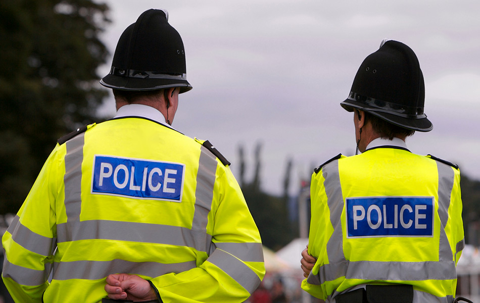 The backs of two uk police walking down the road