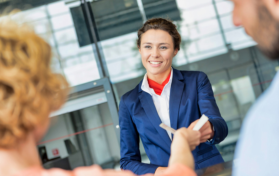 Young air stewardess giving tickets to male and female